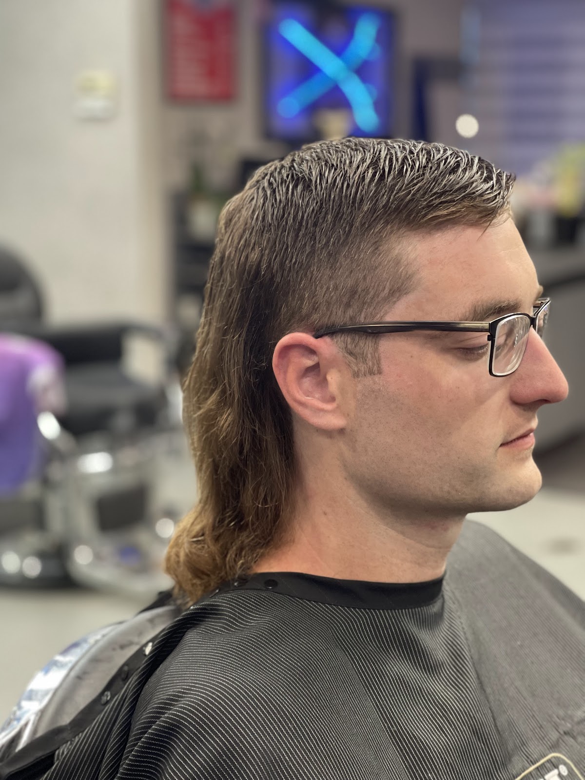 A modern mullet with a clean taper, combed back at the chair